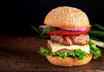 large burger with two fried cutlets, cheese and vegetables
