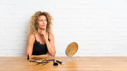 Young woman with lots of makeup brush in a table thinking an idea