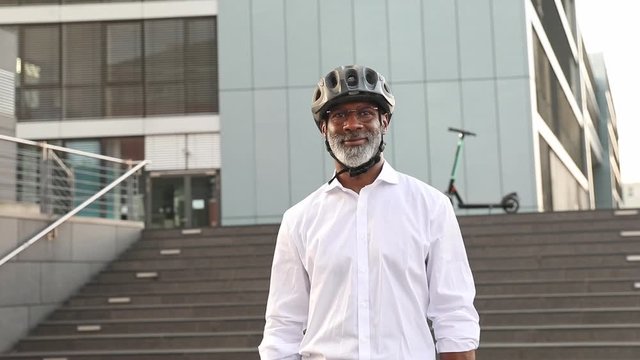 Modern businessman wearing a helmet, e-scooter in the background
