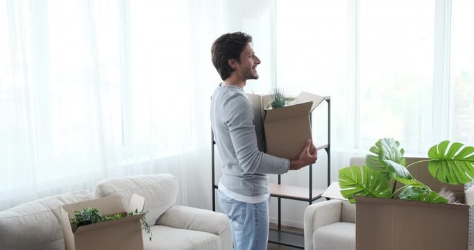 Excited man moving into new home with plant box and celebrating success
