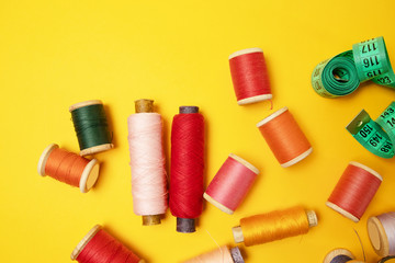 Sewing accessories and fabric on a yellow background. Sewing threads, needles, fabric, buttons and sewing centimeter