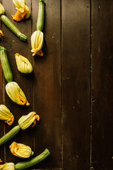 Fresh raw zucchini (courgette) with flowers and Squash blossoms , on a wooden board , top view, natural light.