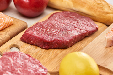 Fresh raw meat on wooden cutting board near lemon6 apples and baguette