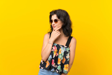 Young woman over isolated yellow background with glasses