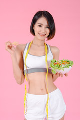 Healthy woman standing holdding vegetable salad diet food and  tape measure in home on pink backgrounds, Healthy concept, Diet concept