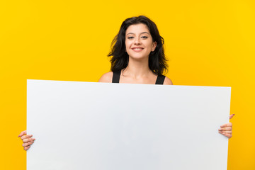 Young woman over isolated yellow background holding an empty white placard for insert a concept