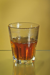Alcoholic drink with ice in transparent glasses. Wine glass with cocktail isolated on yellow background. Frozen drinks on glass table.