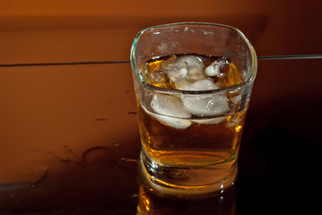 Alcoholic drink with ice in transparent glasses. Wine glass with cocktail isolated on orange background. Frozen drinks on glass table.