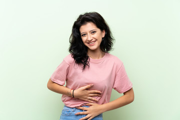 Young woman over isolated green background smiling a lot