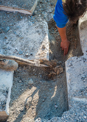 Construction worker is performing a hand-excavation in a restricted section to bury a data transmission line with optical fibers