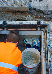construction worker is repairing a pit of the data transmission line with optical fibers, sealing...
