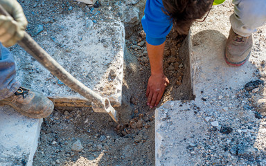 Construction worker is performing a hand-excavation in a restricted section to bury a data transmission line with optical fibers