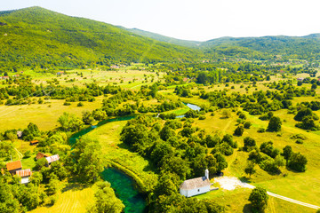 Croatia, countryside landscape, small stone church by Gacka river in region of Lika, aerial view