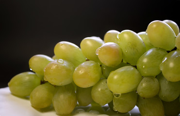 Bunch of green grape isolated on a plate on a black background