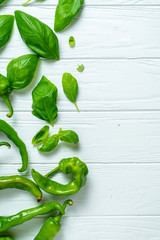 Creative layout with hot pepper and basil in on a white wooden background with copy space. Top view...