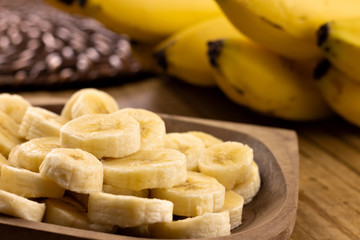 banana slices in rustic pot with bunch of bananas in the background