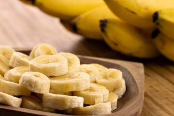 banana slices in rustic pot with bunch of bananas in the background
