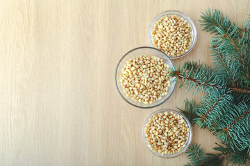 Cedar pine nuts in glass bowls with cones, cedar brunch on wooden background. Top view witn copy space.