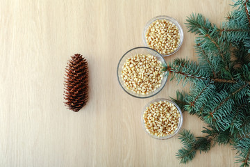 Cedar pine nuts in glass bowls with cones, cedar brunch on wooden background. Top view witn copy...