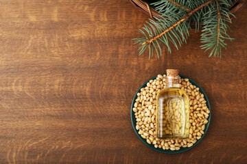 Cedar oil in glass bottle, pine nuts, brunches on a wooden broun background. Top view with copy...