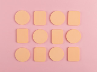 A lot of sponge, a beautiful blender for applying foundation or powder. Flat lay on a pink background, copy space.