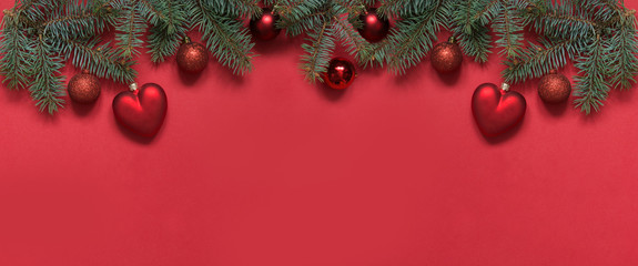 Christmas border of red balls and heart, evergreen branches on red. View from above, flat lay. Xmas. Template, greeting New Year card.