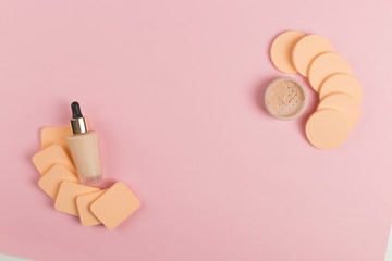 Sponges, a beautiful blender for applying foundation or powder and a bottle of concealer. Flat lay on a pink background, copy space.