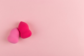 Fototapeta premium Girl hand holds a beauty makeup blender on a pink background, copy space.