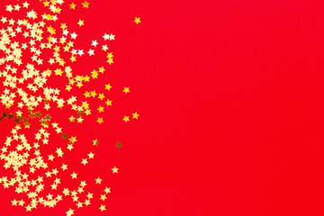 Holiday background with little golden stars on red background. Flat lay, top view