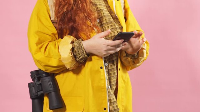 Portrait of a red-haired tourist girl using a mobile phone to view a map