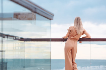 Rear view of fit unidentified young woman tourist admiring magnificent view from hotel terrace to the sea and the horizon. Beautiful woman admires the view after the long-awaited arrival on vacation