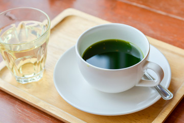 Set of hot matcha (green tea) in white ceramic cup served on wooden tray on table in cafe and coffee shop. Healty beverages of japan for reduce sugar in blood.