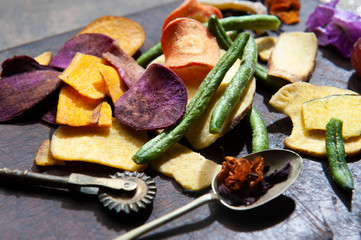 Defocused utensils. Vegetarian cereals. Dehydrated potatoes, carrots, beets, green beans, sea salt, cinnamon grapes. Close view. Autumn colors. Dark background.
