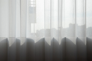 white transparent curtain at glass window with light and shadow. lace curtain.