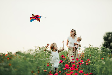 a girl is playing with a toy, her mother is holding a baby