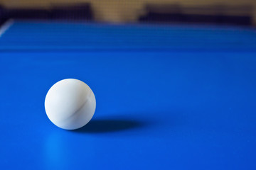 White table tennis ball on blue table. Ball for playing ping pong. Sports concept.