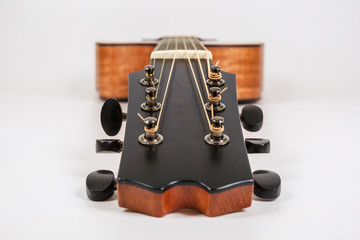 Tuning pegs on wooden machine head of six strings guitar on white background