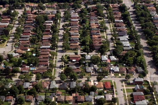 Arial view of house rooftops and city blocks near Toronto and surrounding area as commercial jet comes in to land
