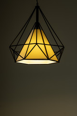 Modern lamp hanging down from ceiling in the dark background.