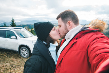 happy tourists couple at peak of the hill with beautiful mountains at background. car travel