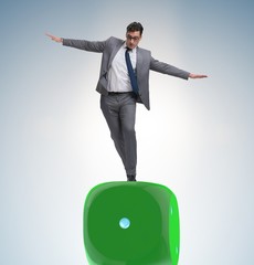 Businessman balancing on top of dice stack in uncertainty concep
