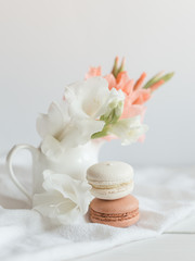 Obraz na płótnie Canvas Two pastel French macarons and flowers in a jar on a white background.