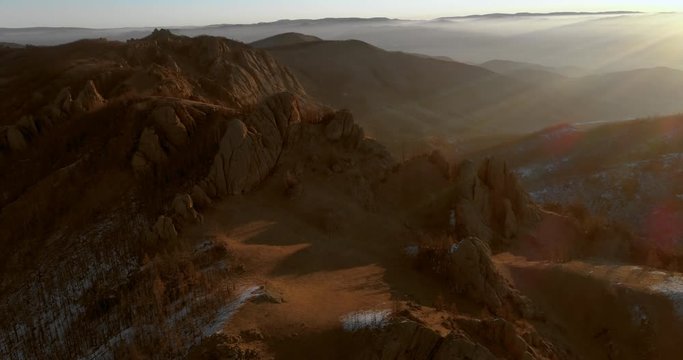 Aerial: Drone moving over rocky mountain peak during sunrise - Northern Countryside, Mongolia
