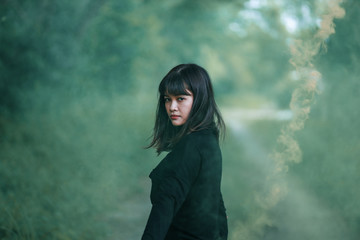 Fototapeta premium Portrait of Asian woman in black cloth with color fire smoke in forest witch concept