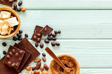 Cook homemade chocolate with bars, nuts, coffee beans on mint green wooden background top view mock up