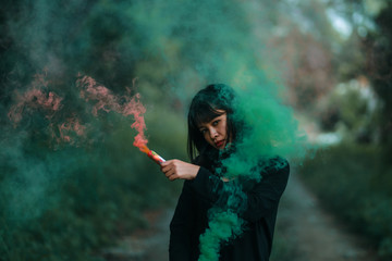 Obraz na płótnie Canvas Portrait of Asian woman in black cloth with color fire smoke in forest witch concept