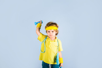 Fitness child. Gym workout. Fitness, health and energy. Child sportsman. Childhood activity. Sport. Sporty boy with jump rope and dumbbells. Boy in sportwear with skipping rope and dumbbells. Success.