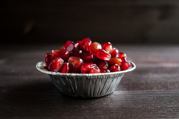 pomegranate seeds in a vase on a wooden background