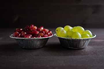 grapes and pomegranate in a plate on a dark background