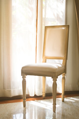 Seat chair with curtain on window.